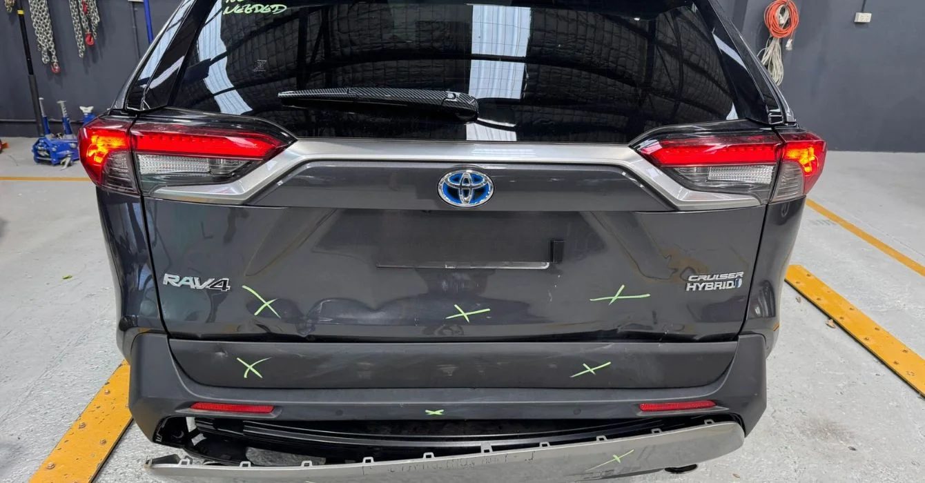 A rear view of a car with visible damage to the boot area, highlighting the restoration process for trunk and rear panel alignment.