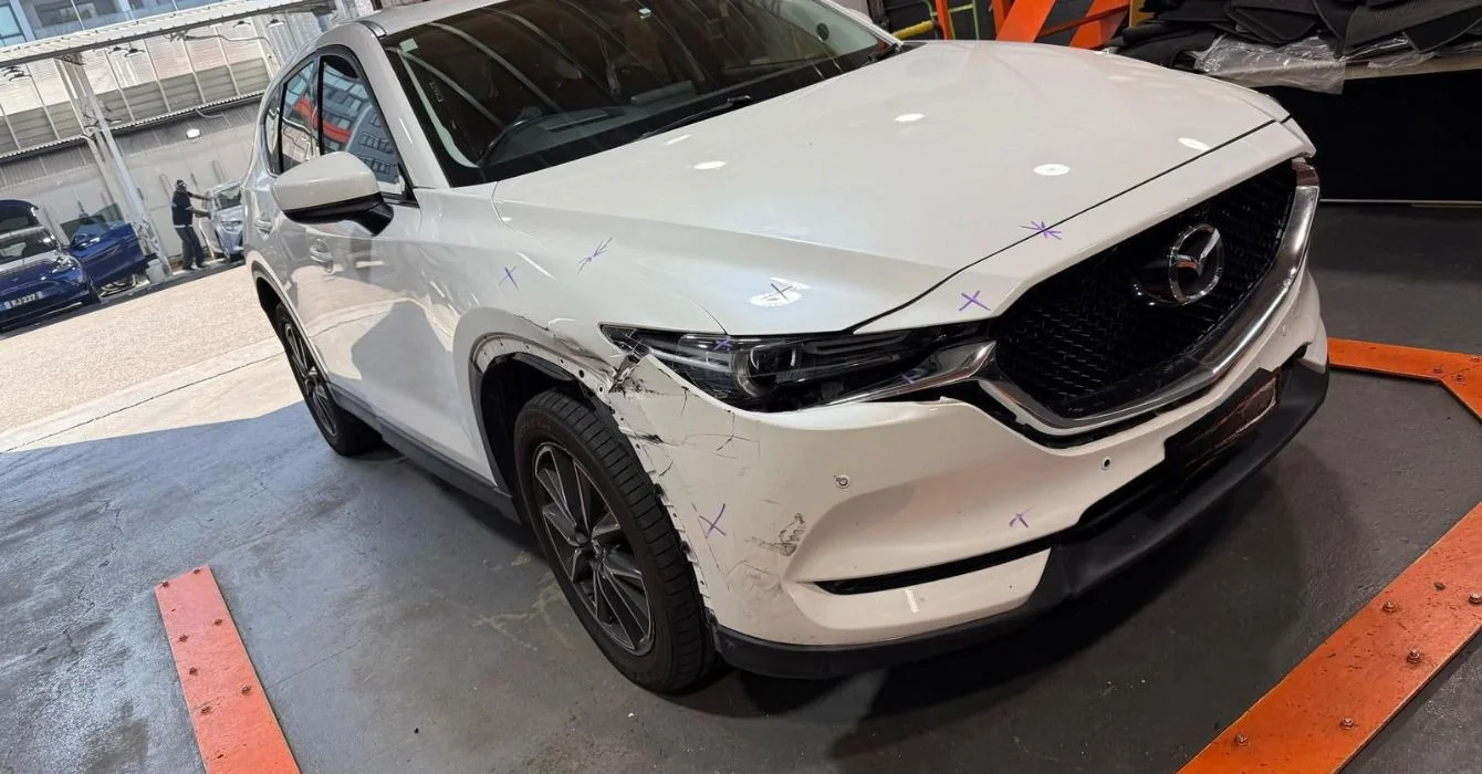Vehicle with visible dent damage above the front right wheel and door area, showcasing side panel impact repairs.